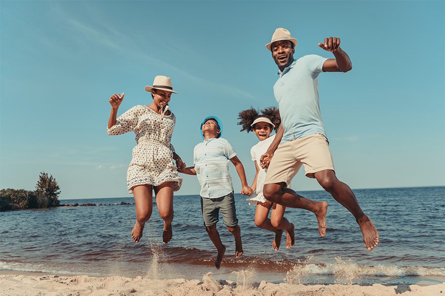Personal Insurance - Portrait of a Cheerful Family with Two Kids Having Fun Playing Together in the Ocean During a Summer Vacation
